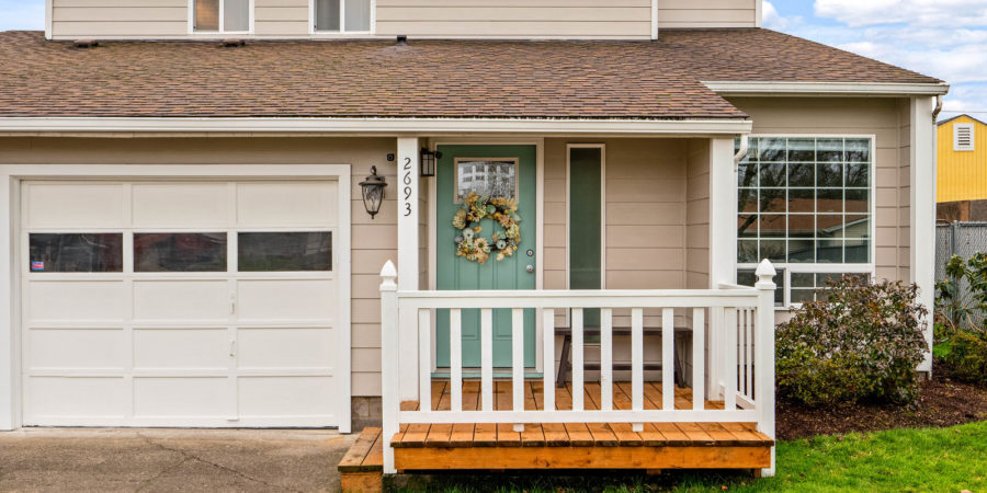 Tan house with teal door and porch.