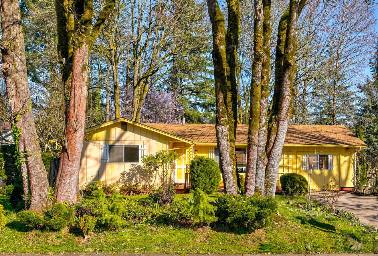 Yellow ranch house surrounded by trees.