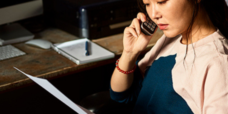 Woman reviewing documents while on phone call.