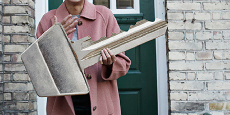 Happy woman holding oversized house key.