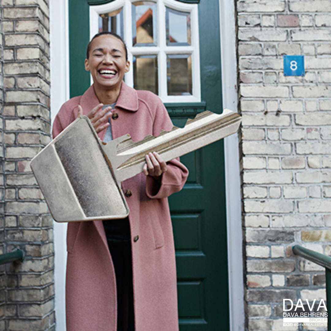 Happy woman holding oversized house key.