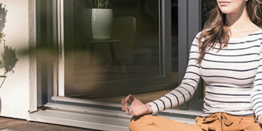 Woman meditating outdoors by patio door.