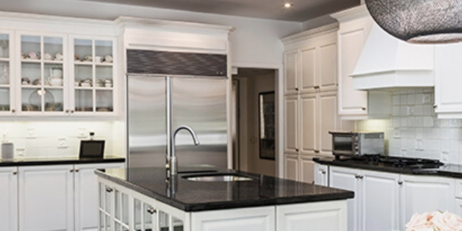 Modern white kitchen with island and black countertops.