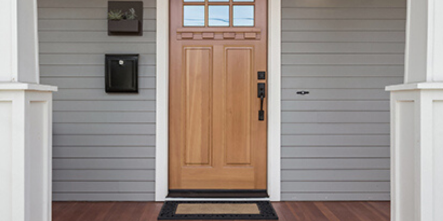 Wooden front door on gray house.