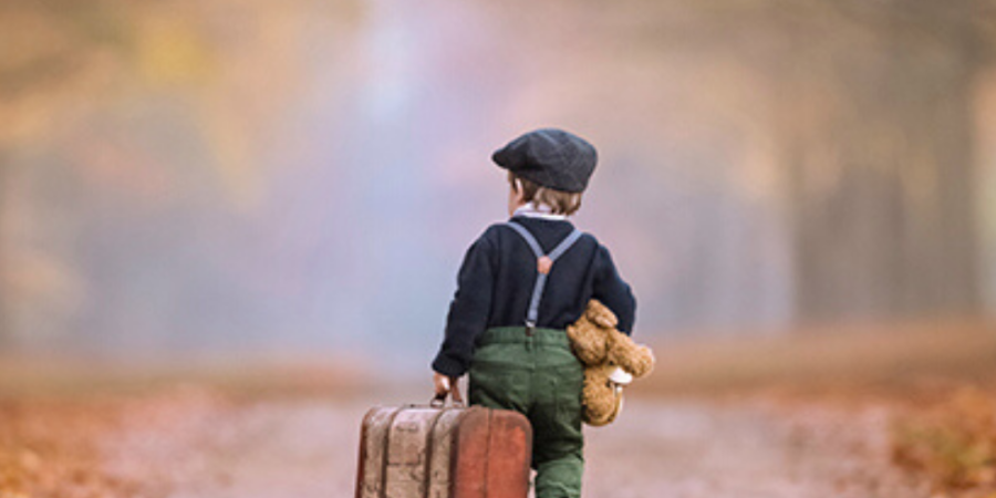 Child walks away with suitcase and teddy.