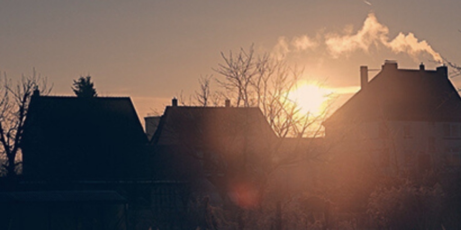 Sunrise silhouettes houses winter scene.