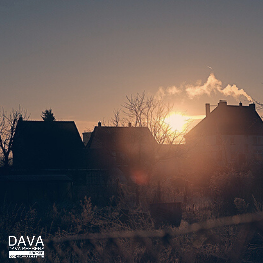 Sunrise silhouettes houses winter scene.