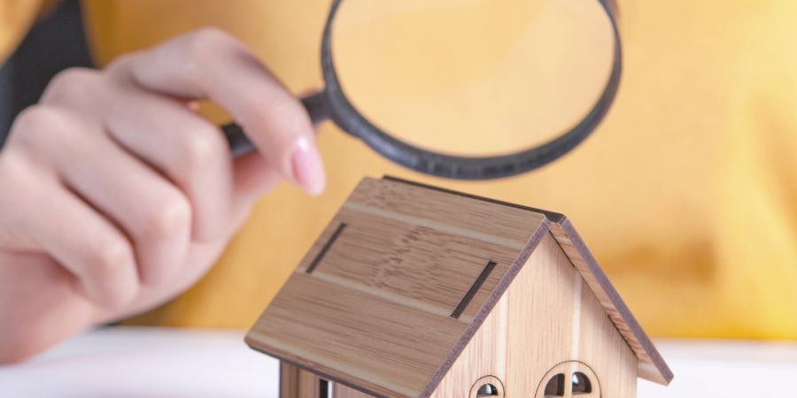 Hand inspecting a wooden house model.