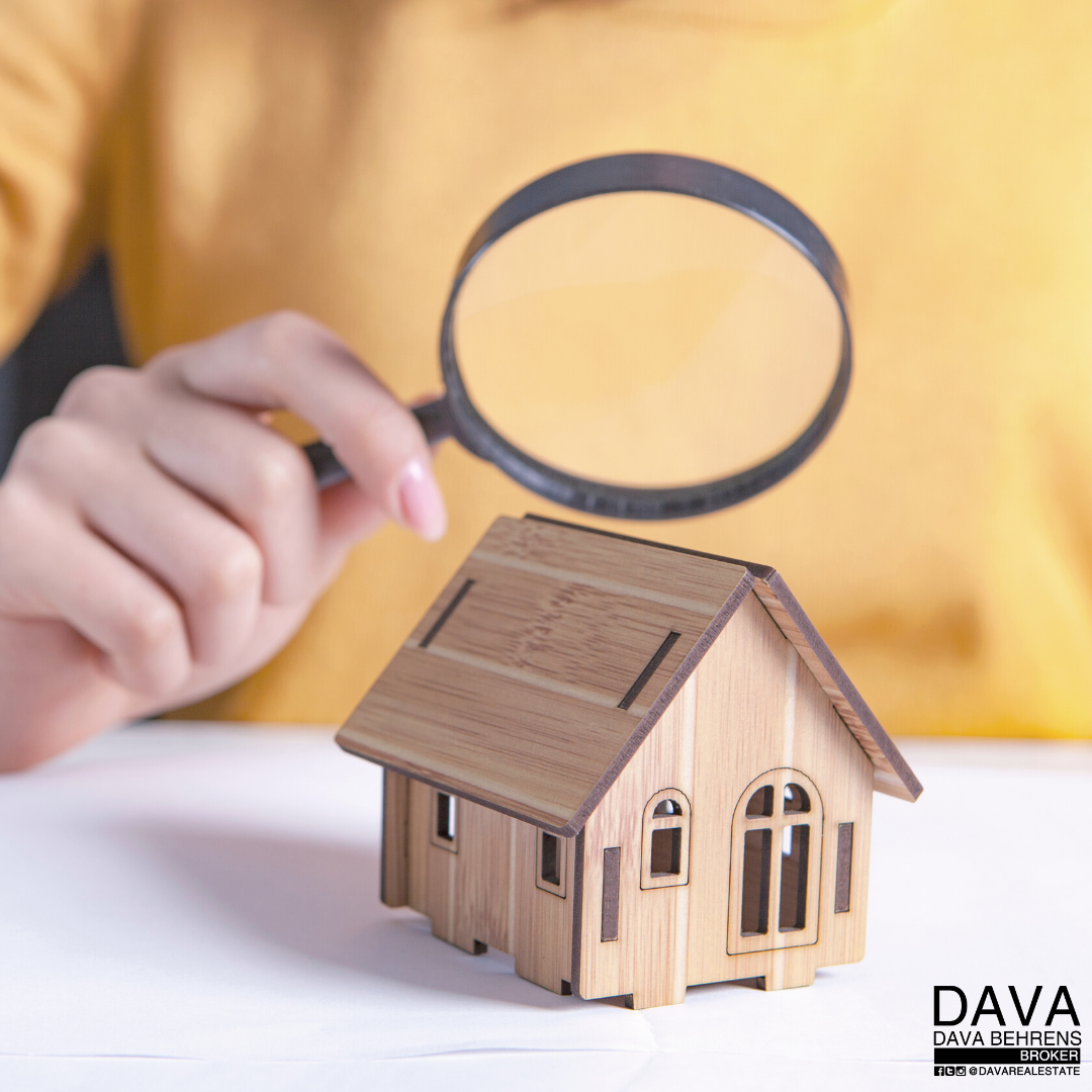 Hand inspecting a wooden house model.