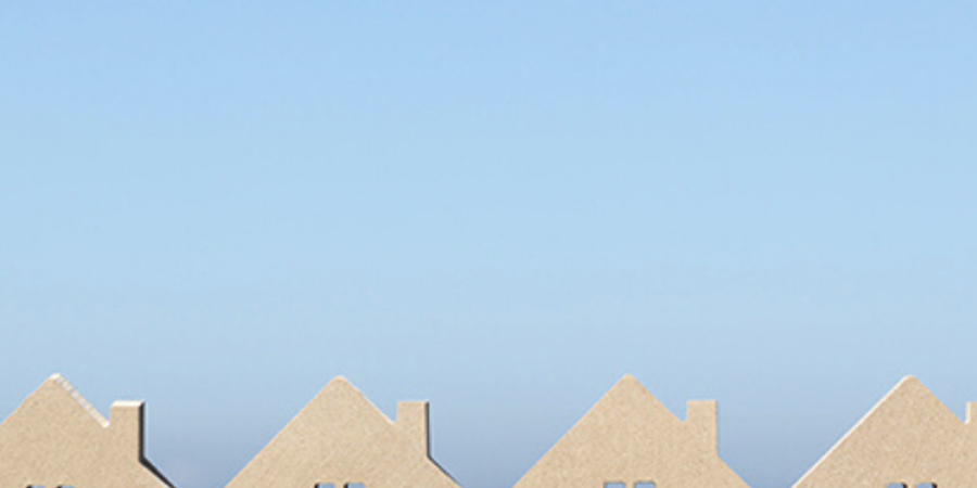 Row of miniature houses under blue sky.