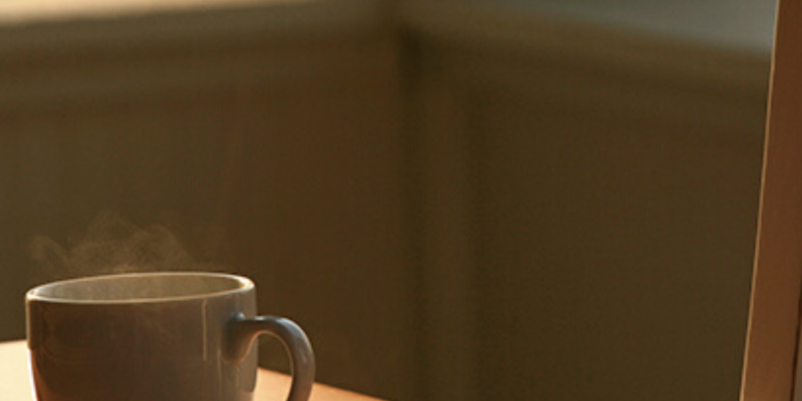 Steaming coffee mug on wooden table.