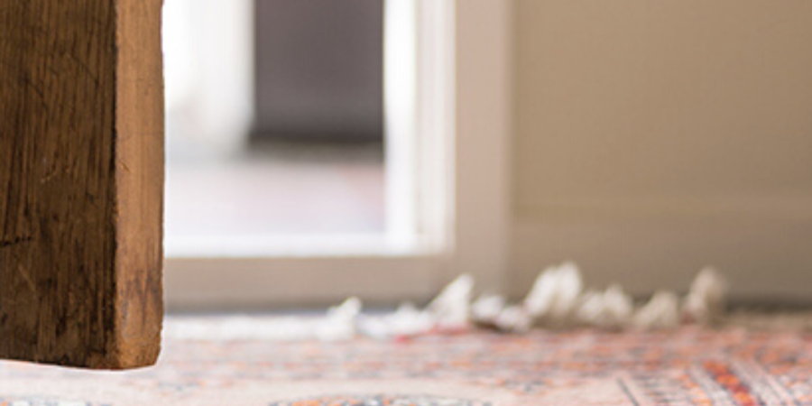 Wooden door open to patterned rug.