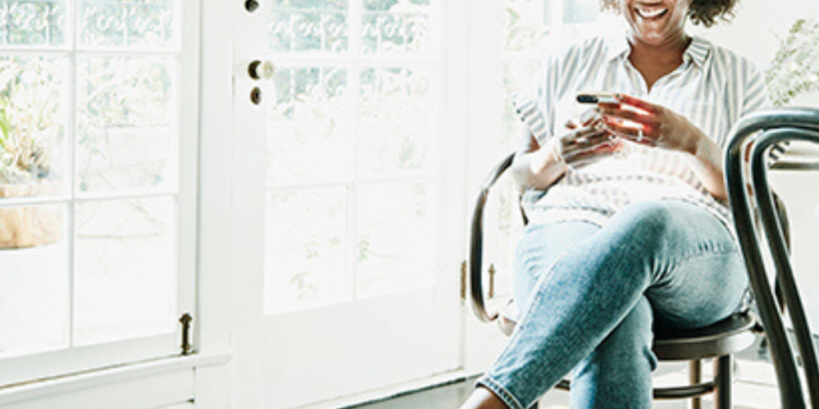 Smiling woman using phone in chair.