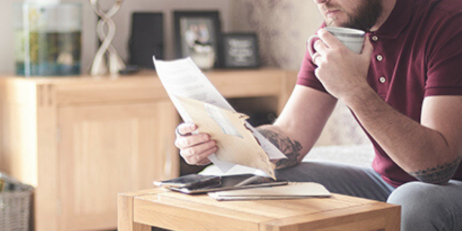 Man reviewing paperwork with coffee.