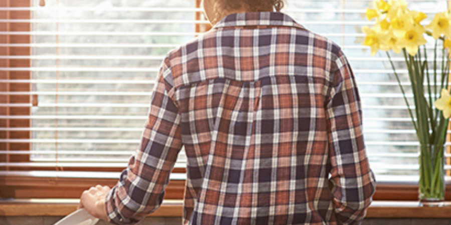 Woman stacking dishes by window.