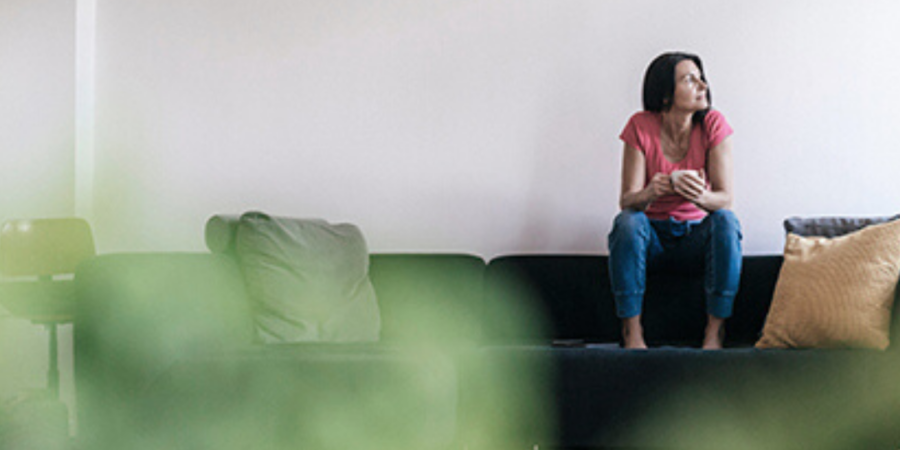 Woman sitting on couch, pensive.