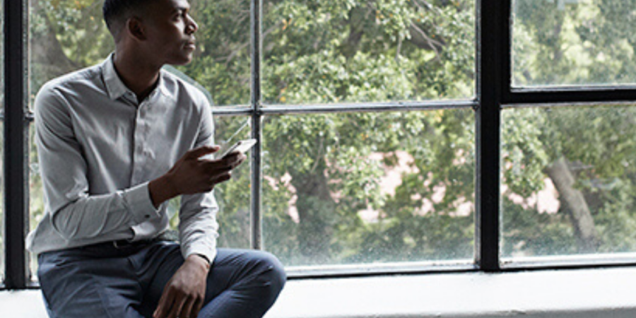 Man sits by window using phone.