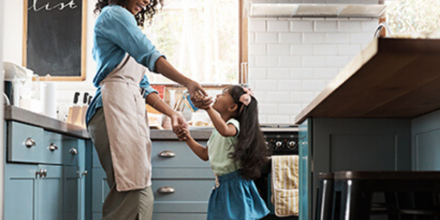 Mom and daughter dancing in kitchen.