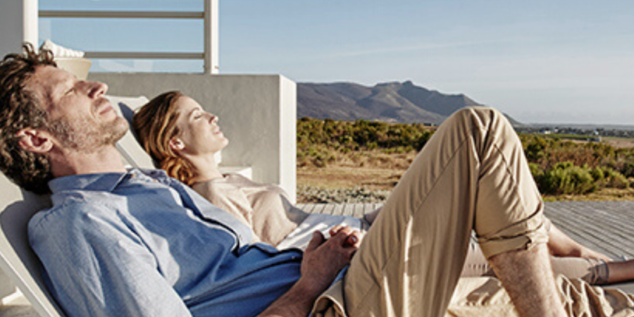 Couple relaxing outdoors on lounge chairs.