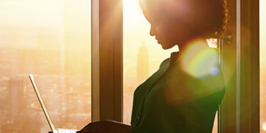 Woman working on laptop by window.