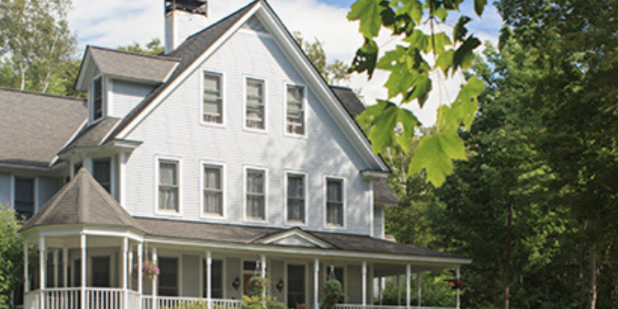 Large white house with wrap-around porch.