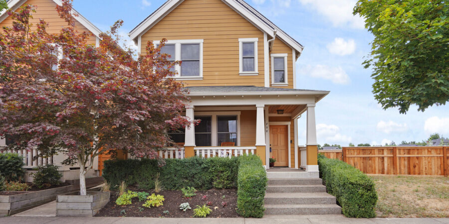 Mustard yellow house with porch and landscaping.