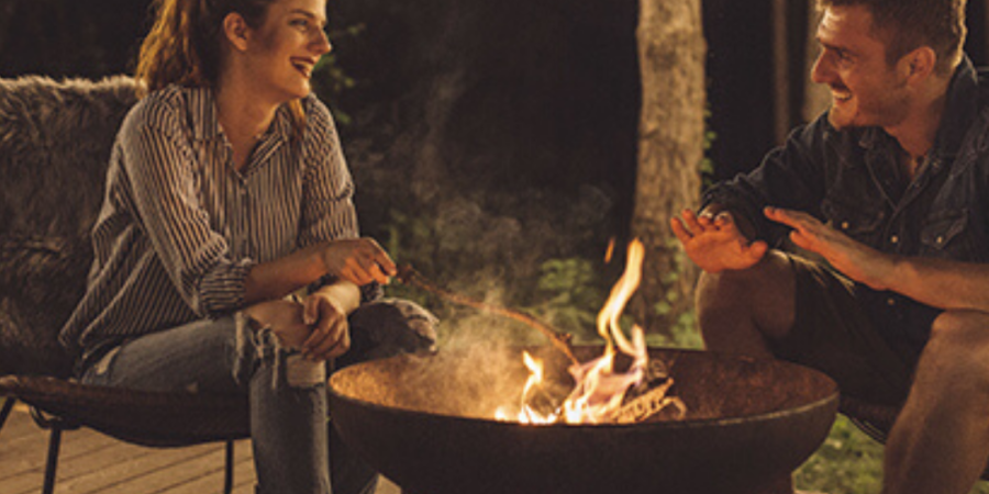 Couple roasting marshmallows by campfire.