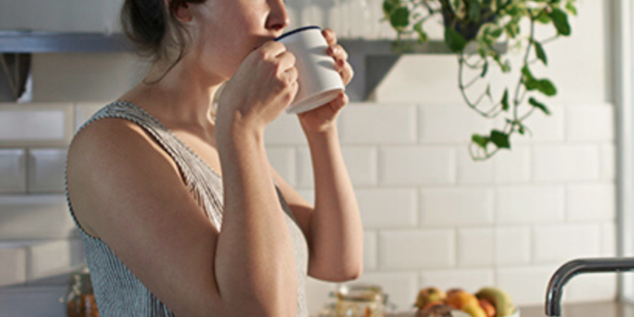 Woman drinking coffee in kitchen.