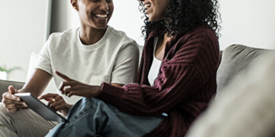 Here's an 8-word alt tag for the image: Happy couple reviewing documents on tablet at home.