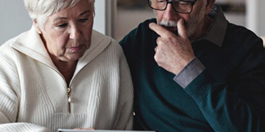 Senior couple reviewing documents online.