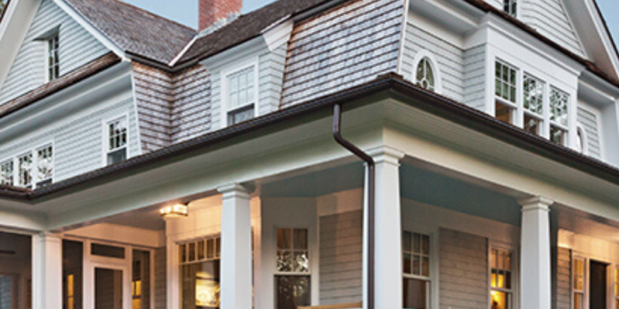 Large gray house with wrap-around porch.