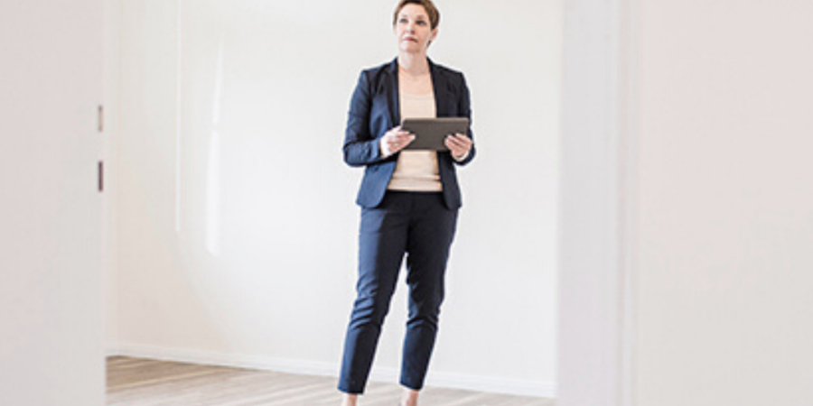 Businesswoman in empty room, holding tablet.