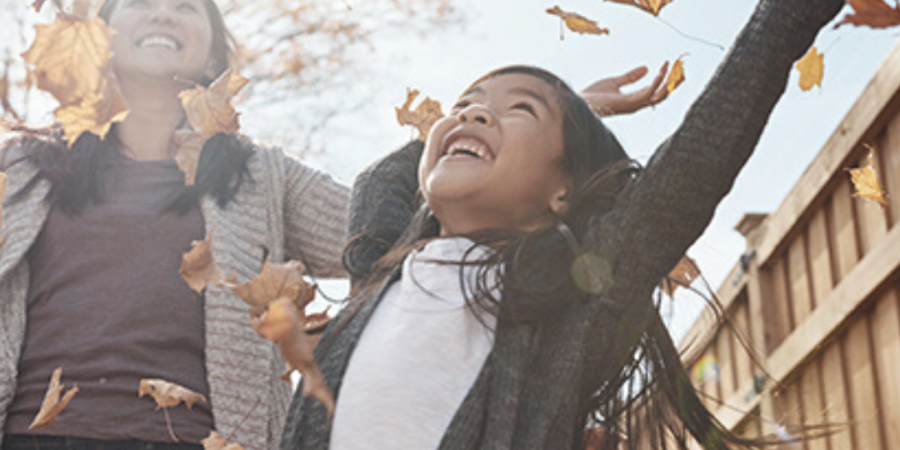 Mother and daughter playing in autumn leaves.