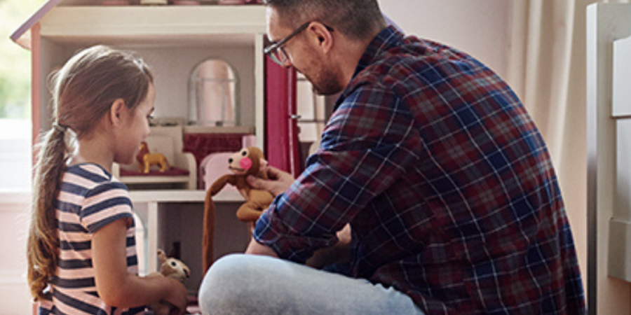 Father and daughter playing with dollhouse.