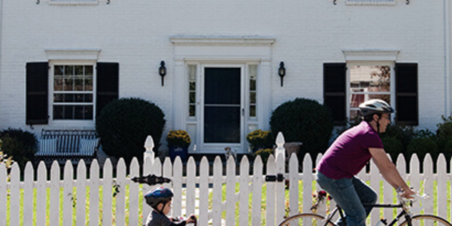 Family biking in front of white house.