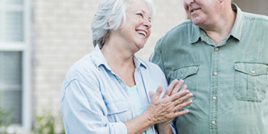 Happy senior couple outside their home.