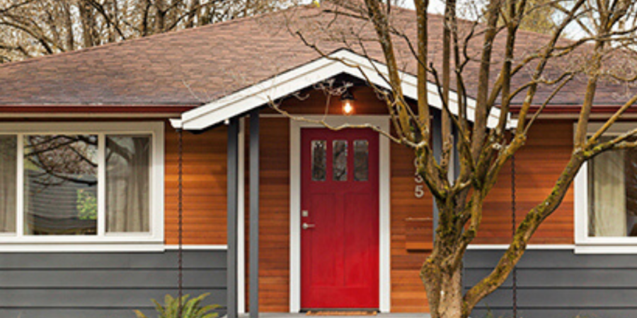 Red door house, gray siding, landscaping.