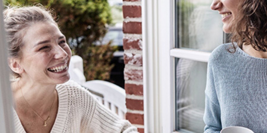 Two women chatting at an open window.