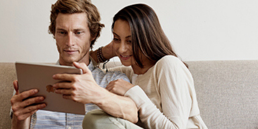 Couple using tablet on couch together.