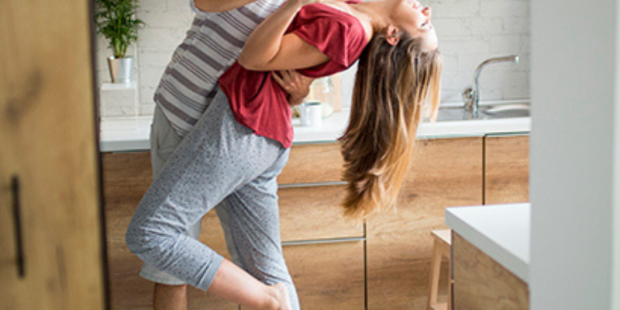 Happy couple dancing in kitchen.