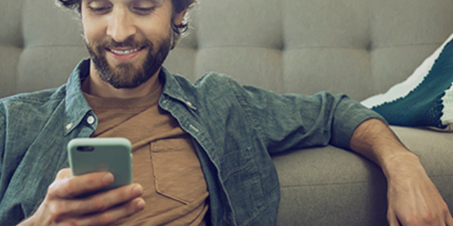 Man relaxing on couch, using phone.