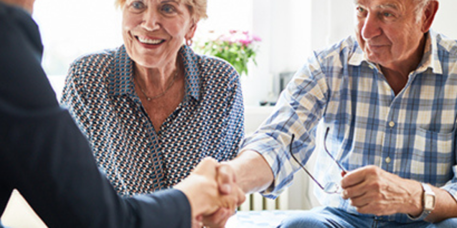 Senior couple shaking hands with realtor.