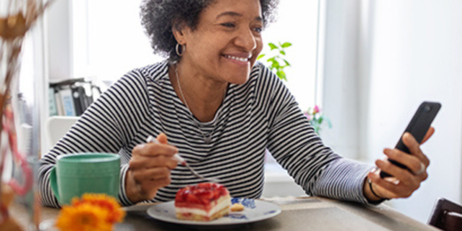 Woman enjoys dessert while using phone.