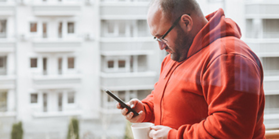 Man using phone, coffee on balcony.