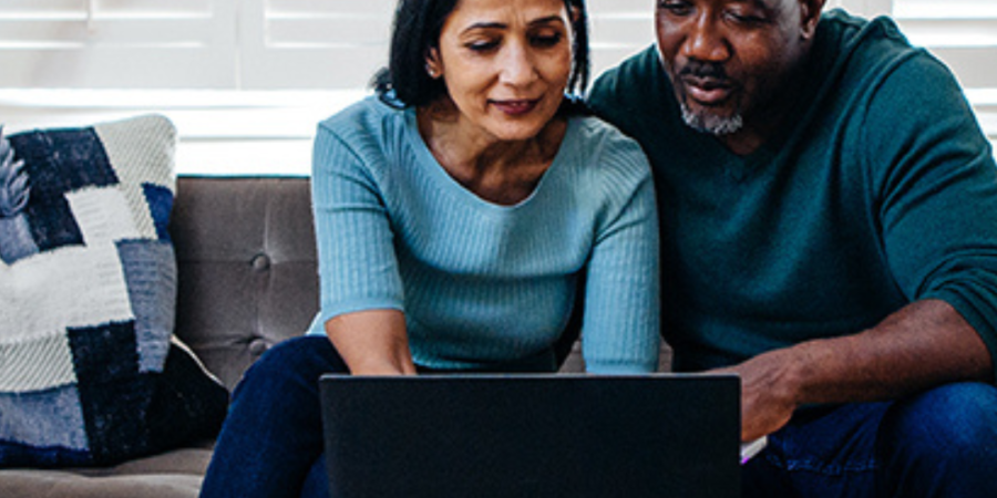 Couple using laptop, looking at screen.