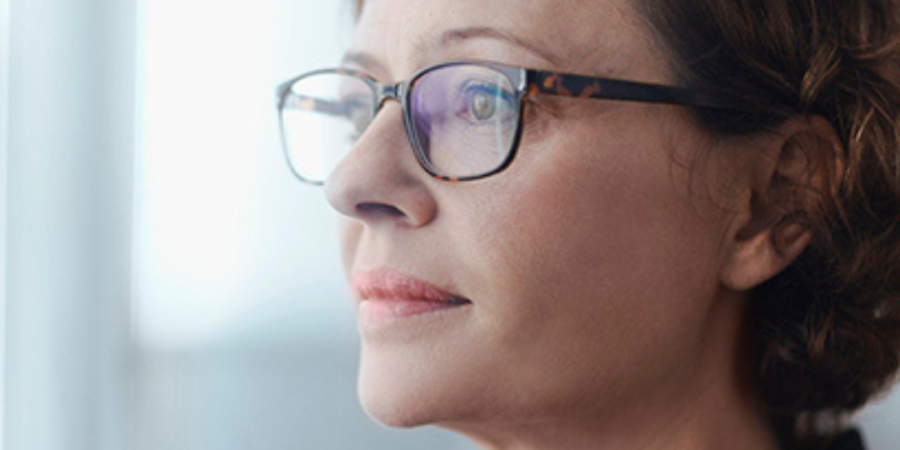 Woman in glasses looking thoughtfully.