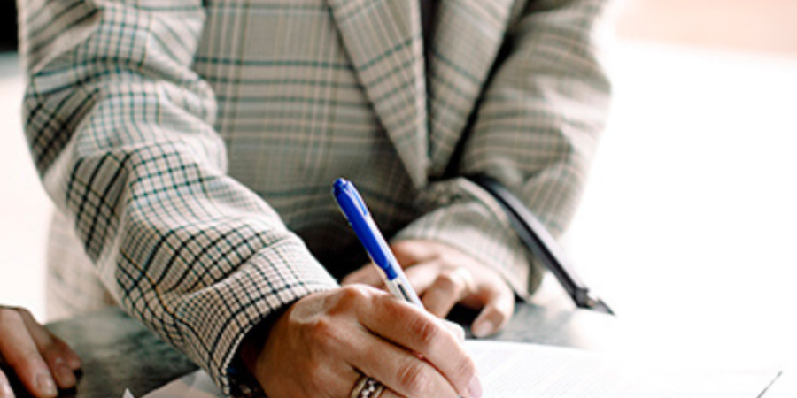 Woman signing a document with a pen.