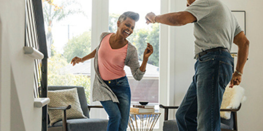 Happy senior couple dancing at home.