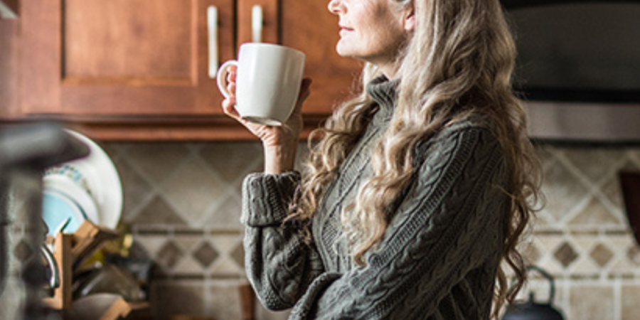 Woman enjoying coffee in her kitchen.