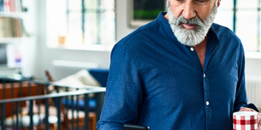 Senior man using phone and drinking coffee.